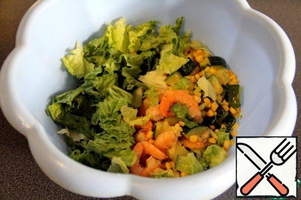 In a deep bowl, tear the lettuce leaves with your hands, add the shrimp, zucchini and corn.