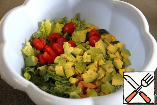 Cut the tomatoes in half, cut the avocado into cubes and sprinkle with lemon juice and add to the salad.