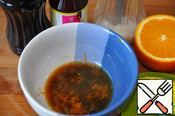 Making a marinade. Remove the zest from the orange, squeeze out the juice, add soy sauce, sugar and sesame oil. Stir.