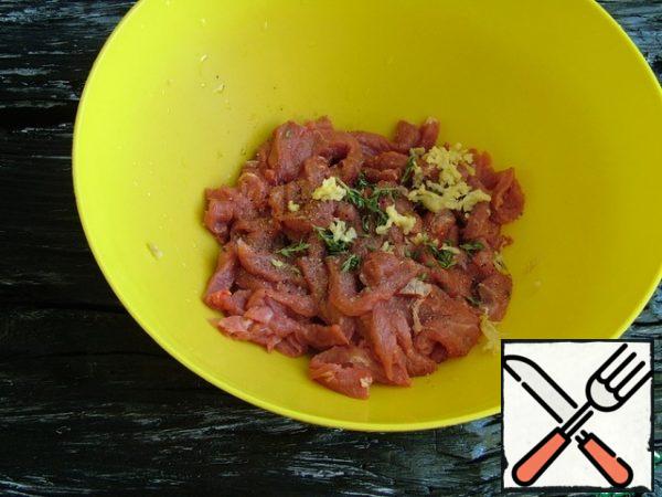 Cut the beef tenderloin into strips, sprinkle with salt, pepper, thyme leaves, crushed garlic, 20 ml of olive oil, mix and leave to marinate for 10 minutes.