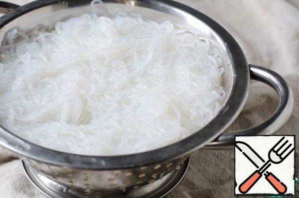 Now you need to cook rice noodles, for this you need to boil water in a saucepan, add salt. Add the noodles, stir, and cook for 1-2 minutes. Toss in a colander and rinse with cold water.