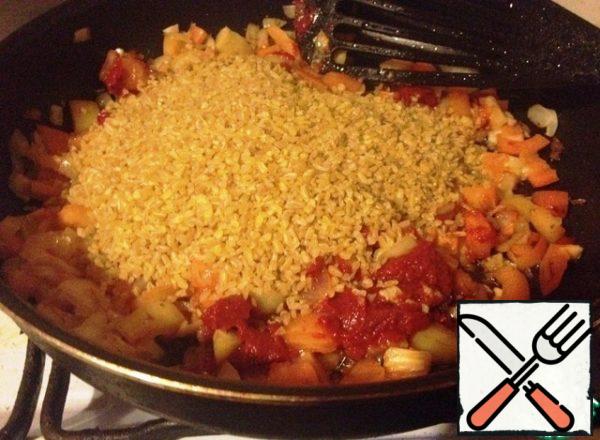 Peel and chop the garlic. Add to the saucepan along with tomato paste, spices, bulgur. Stir-fry for 2 minutes.