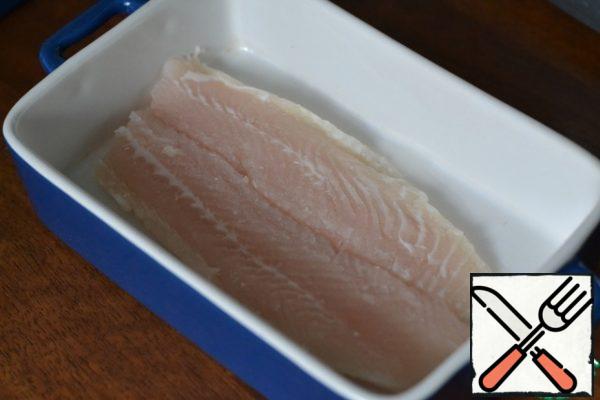 Grease the baking dish with sunflower oil.
Wash and dry the fish. We put it in the form.