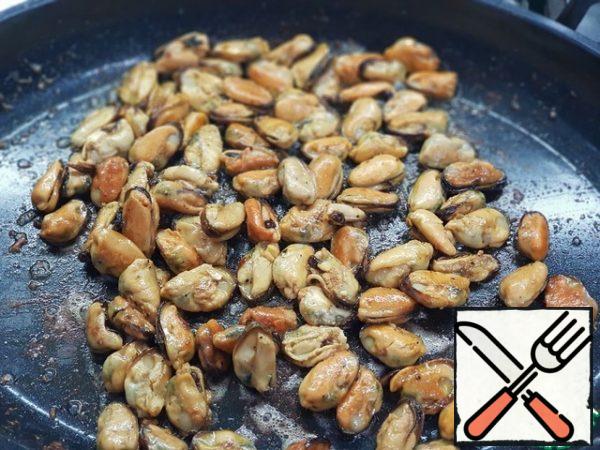 Throw the thawed mussels on a preheated frying pan Over medium heat.
