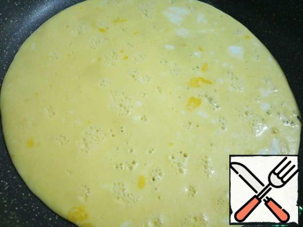 The pan is slightly warmed up, you can wipe it with a napkin soaked in vegetable oil, but do not pour oil into the pan. Pour our egg mass and bake under the lid, on a very slow fire pancake. When the top also grabs, we do not turn it over, but simply put it on a dish. With the remaining milk and eggs, bake the second "pancake".