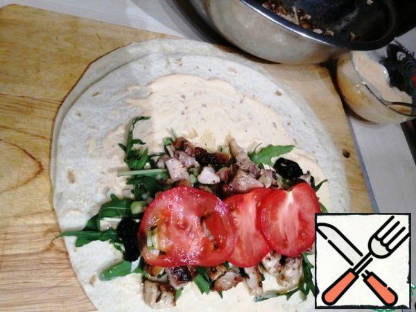 Take pita bread or wheat tortilla. Lubricate the sauce.
Spread on one half of the arugula, radishes, cucumber, chicken, tomatoes.