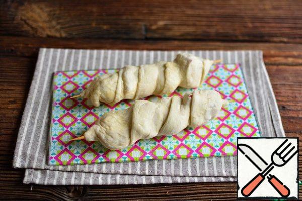 Roll out part of the dough lengthwise in the form of a ribbon and wrap the skewers, pinch the edges well on the skewer.