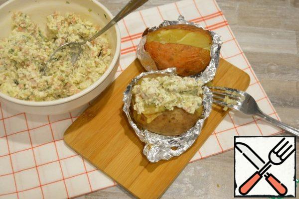 Cut the finished potatoes with a knife. Use a fork to gently mash the pulp and put a good portion of the filling inside.

It is very tasty to mix the filling with the hot pulp, so that the cheese is slightly melted, and the garlic reveals its flavor.