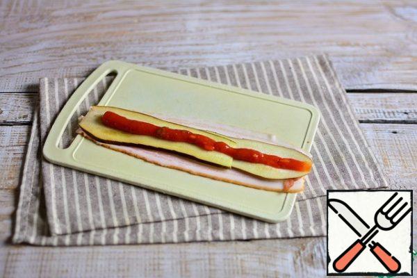 On 2 strips of bacon (next to it, so that it is wider), spread 2 strips of eggplant along the entire length of the bacon.
Top with a strip of ketchup.