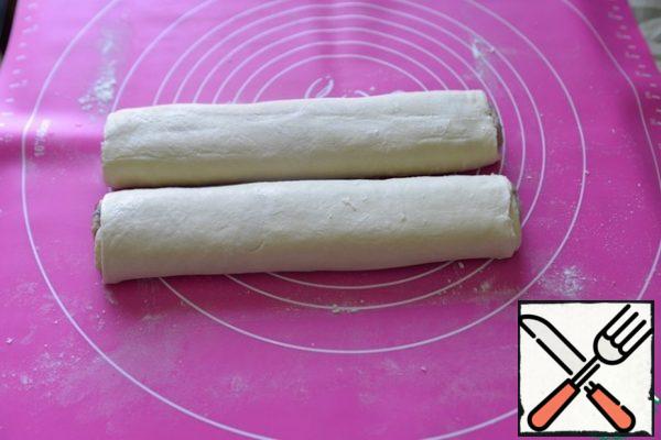Put the "sausage" on the edge of the dough and roll it into a roll. The edge of the dough should be at the bottom.