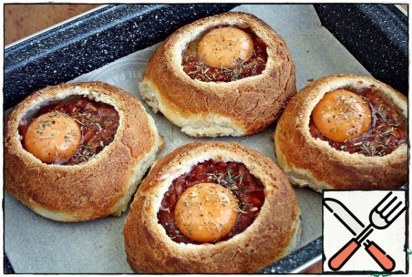 Then in each bun on sausage with ketchup, break one egg, salt and, if desired, add your favorite spices. I have large buns, I also took large eggs, they fit without problems and there is still a lot of free space. If you have medium-sized buns, it is better to take small eggs so that they do not leak out, and if small, you can pour out one yolk.
