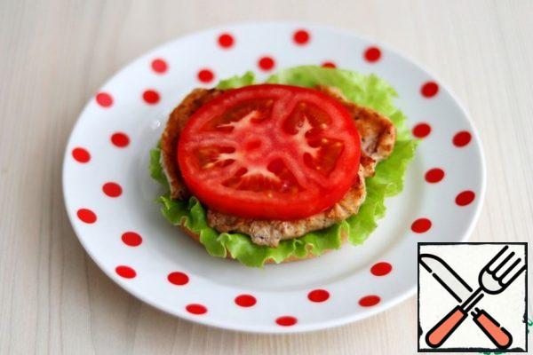 Cut the hamburger bun into two parts. On the lower part, put a lettuce leaf, then fried Turkey breast fillet, then grease the fillet with the prepared avocado and garlic cream, then a plastic tomato, then a lettuce leaf again.