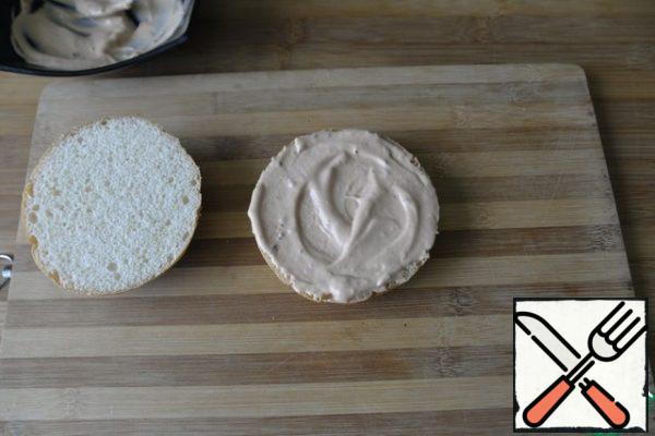 It is better to collect the Burger immediately before use, so as not to get wet. We take a hamburger bun: ready-made or self-made. I have ready with sesame seeds, cut with a knife, better with a file in half. Lubricate the lower part liberally with sauce.