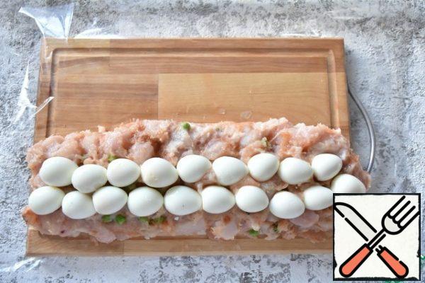 Spread half of the minced meat on a heat-resistant or collagen film. Put the boiled and shelled quail eggs in the middle.