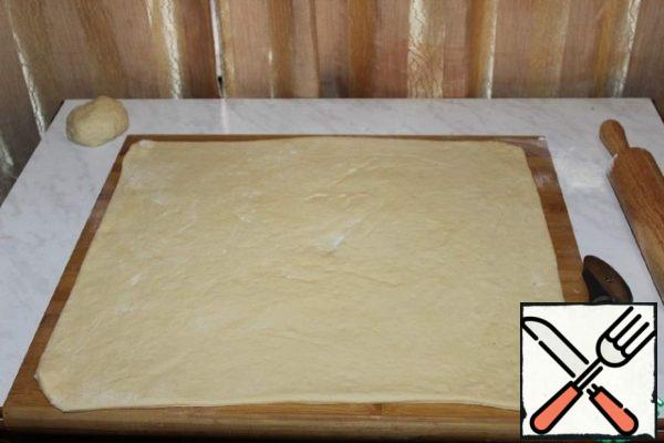 Roll out into a rectangular layer. And grease with butter.
