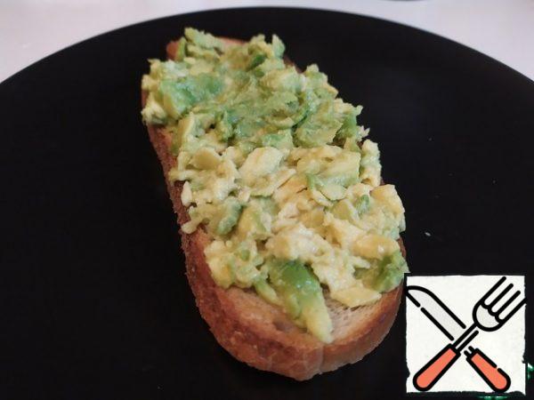 Peel the avocado. On each piece of bread, put one half of the avocado and mash it.
