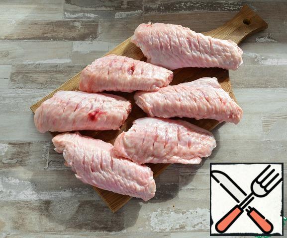 The elbow part of the Turkey is best suited for this dish. Rinse the wings, blot with a napkin and make cuts with a knife as in the photo, so that the wings are better marinated and cooked.