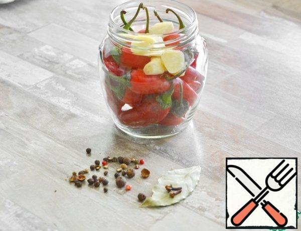 The calculation of products is given for a half-liter jar. Wash and sterilize the jar. Wash the lid and boil it. At the time of canning, the lid should be hot (keep it in boiled hot water)

I have 15 peppercorns in my jar. Lay it tightly, but do not tamper, so that the peppercorns do not burst. Add the chopped garlic, Bay leaf, a couple of whole cloves and pepper to the jar. I have a mixture of 5 peppers, you can take any peas.