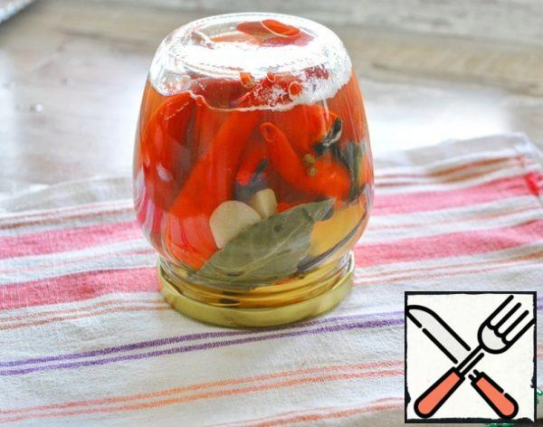 Pour the boiling marinade over the peppers in the jar, screw the hot boiled lid on. Turn it over on a towel and wrap it up until it cools down. After cooling, make sure that the lid is "sucked in" - it is concave inside.

The pepper will be marinated for about a month. The jar preserved in this way can be stored in the room. After opening the jar, it will need to be stored in the refrigerator.