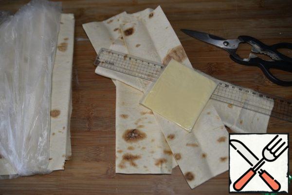 We cut the roll into strips in width, commensurate with the plate of cheese that we will wrap. Convenient to cut with scissors. We will need 2 strips for each envelope. I have strips of 8x27 cm.