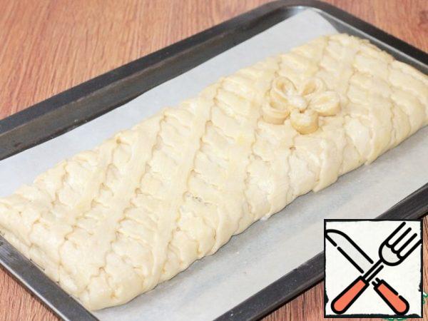 Coat the baking pan with baking paper and grease with butter. Transfer the pie to paper.
Mix the melted butter (3 tbsp) with liquid sour cream (1 tbsp) and grease the pie. Put the baking sheet in the oven and turn on the minimum temperature of 40 C.