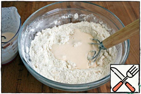 Add kefir to the flour in parts and knead the dough with a whisk (spoon).