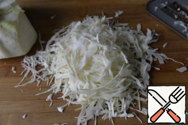 Preparing a cabbage salad. Thinly shred the cabbage, add salt, sugar, vinegar and lightly knead, do not press hard until the juice.