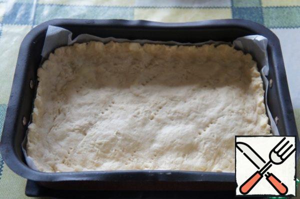 Take the dough out of the refrigerator. Grease the form with oil. Roll out the dough a little, put it in a mold and knead it with your hands over the entire surface, making a side. Repeatedly prick with a fork and put in the preheated oven for 15 minutes.