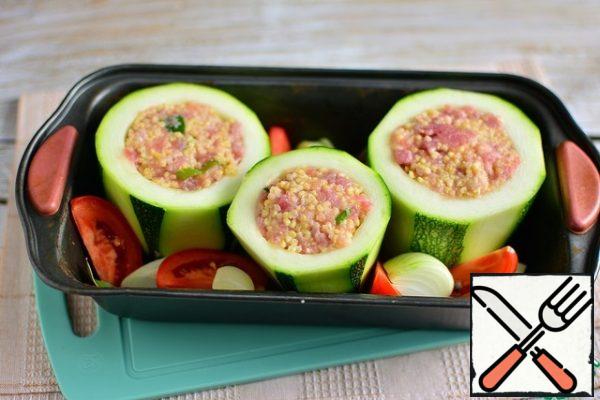 Put the chopped tomatoes, onion, 1 clove of garlic, bay leaf and allspice in a mold around the zucchini.