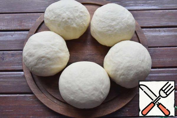 I got five rolls, weighing 115 grams. You can make them smaller.
Roll each part of the dough into a ball, put it on a Board and cover with a film or napkin. Leave for another 30 minutes.