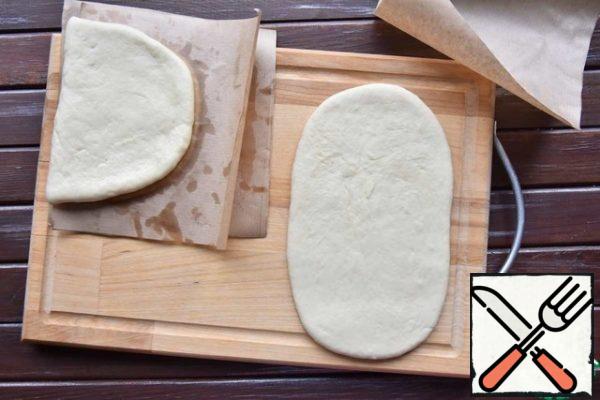 Cut out 15x15 cm squares from parchment paper. Roll out each piece of dough into an elongated flat cake, oval in shape. Lightly brush the surface with vegetable oil.