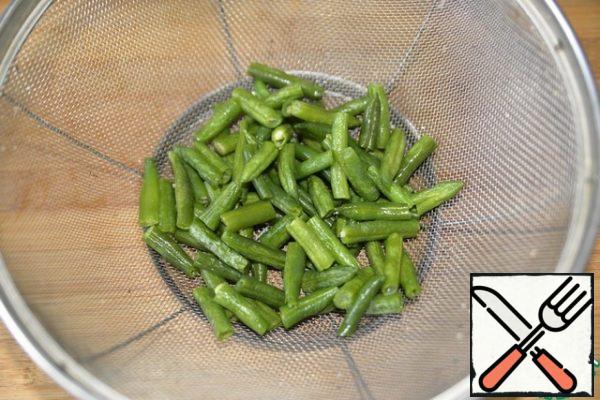 If the string beans are frozen, then let them thaw. If fresh from the garden, then wash, cut off the tips, cut into pieces 2-4 cm.