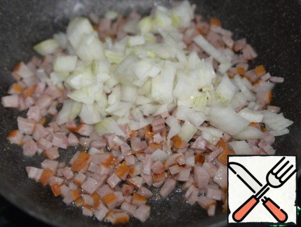 Onions are also cut into cubes, put to the sausages, fry until transparent.