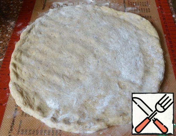 On a dusty Mat, stretch the dough into a circle, 1 cm thick.