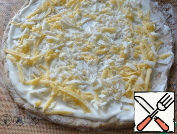 Brush the dough with sour cream and sprinkle with grated cheese.