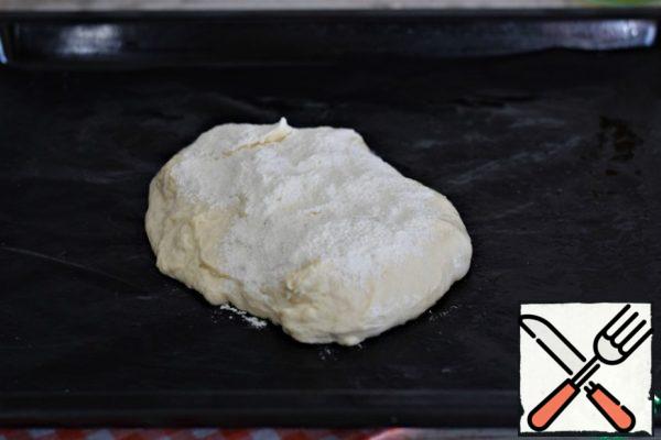 Using a spatula (spoon), place half of the dough on a baking sheet lined with Teflon sheet, parchment or silicone Mat. (it is better to grease the parchment with vegetable oil) Sprinkle the dough with flour. 10 grams will be enough.