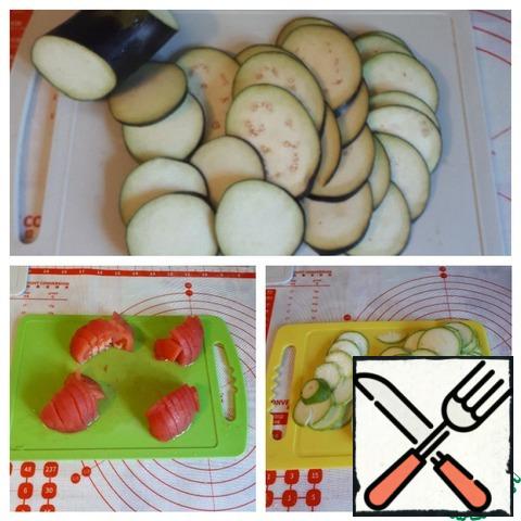 Prepare the vegetables. Cut the eggplant and zucchini into thin circles about 2-3 mm thick. I remove the skin from the tomato and pour boiling water over it, ( but this is optional), cut into pieces. Zucchini and eggplant are better to take not thick.