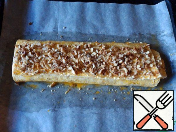 Top the roll with egg yolk and sprinkle with chopped walnuts. Bake in the oven for about 10 minutes at 180 degrees. Serve the roll with tea or coffee.