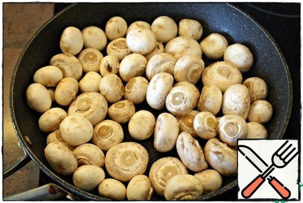 First of all, heat a dry frying pan well over high heat, then reduce the heat to just below average, spread the mushrooms, cover with a lid. When a large amount of liquid is released from the mushrooms, remove the lid and evaporate.