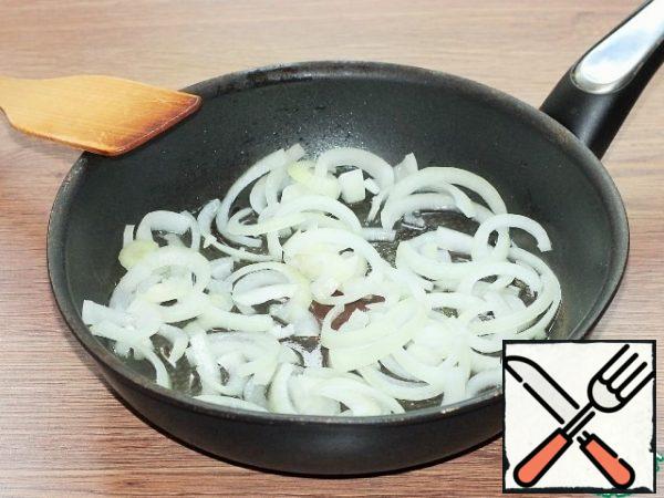 In garlic oil, fry the peeled and cut onion in half rings until transparent.