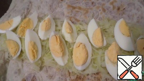 Add quarters of boiled egg. Roll it up. Additionally, moisten the left and right edges of the roll, and press hard so that the filling does not fall out.I use a silicone Mat. I put pita bread on it, twist the roll on it, and then bake it on a baking sheet.