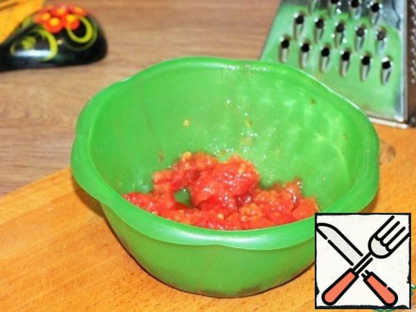 The second tomato is grated on a large grater, the skin is removed.