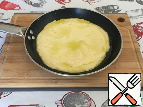 Pour olive oil into the pan for frying. For this amount of dough, I take a frying pan with a diameter of 25 cm. Then spread the dough on the surface and carefully level it.