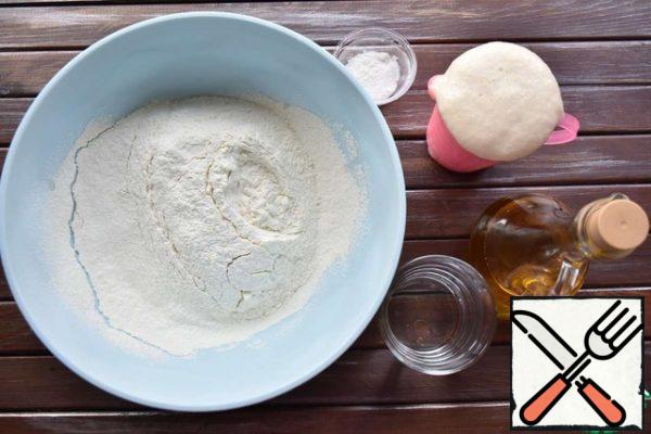 In a large bowl, sift the flour and add salt. Enter the activated yeast, pour in olive oil and water.