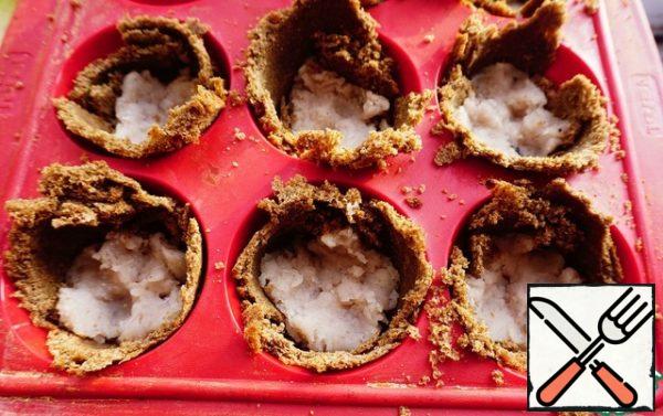 Start assembling mini-quiches. At the bottom of our bread baskets we spread minced fish.