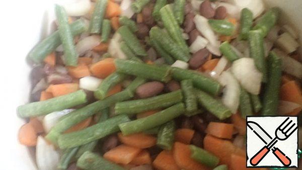 Cut the carrots and onions and add them to the pan with the beans.
Add the string beans to them and cook under the lid for 5 minutes.