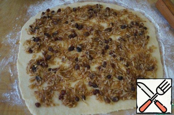 Divide the dough into two parts. Roll out a thin layer and lay out half of the filling evenly.