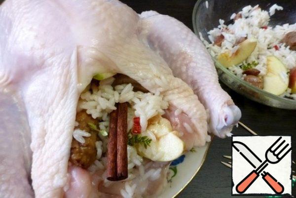 Stuff the chicken with the prepared filling, stick a cinnamon stick in the rice. Stab the abdomen with toothpicks so that the filling does not fall out.