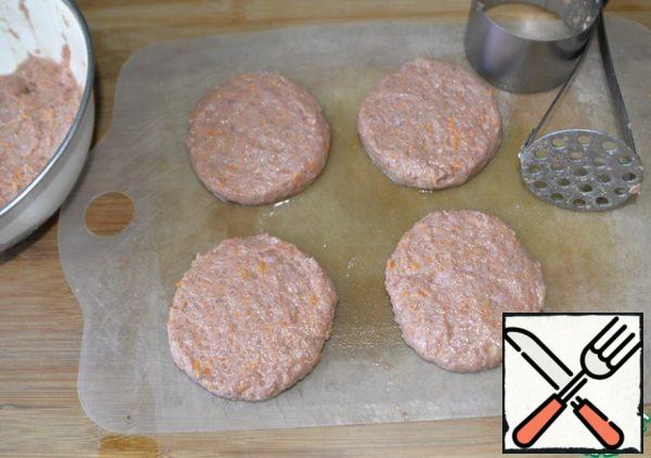 Since these cutlets are prepared without breadcrumbs, but the minced meat is too thin, then for the convenience of working with minced meat, we lubricate the Board with oil.
We form round cutlets about 2 cm high. It is convenient to do this with the help of a cooking ring and a pusher.