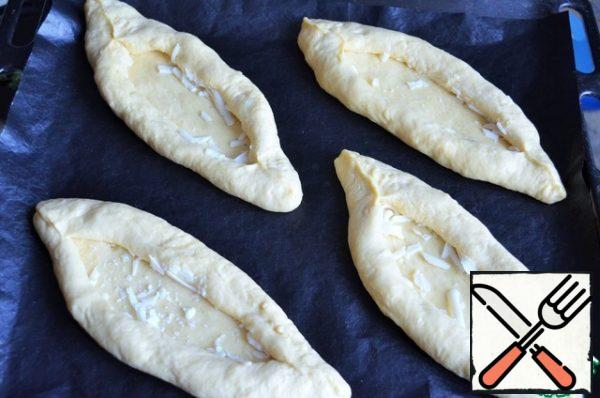 Roll up the sides of the roll, form the boats. Cover the blanks with a film, leave for proofing. Turn on the oven to warm up.